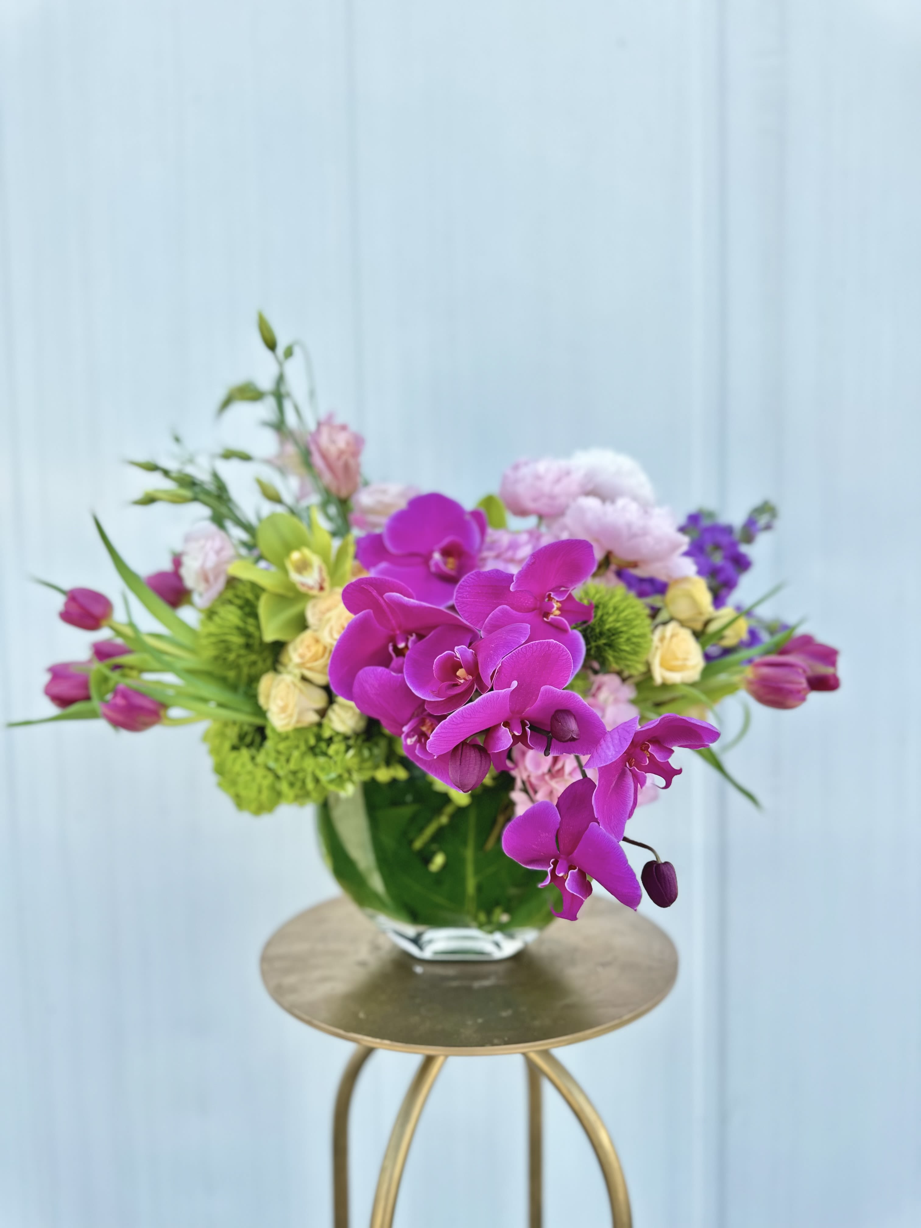 Purple orchids and mixed pastel flowers in a glass vase