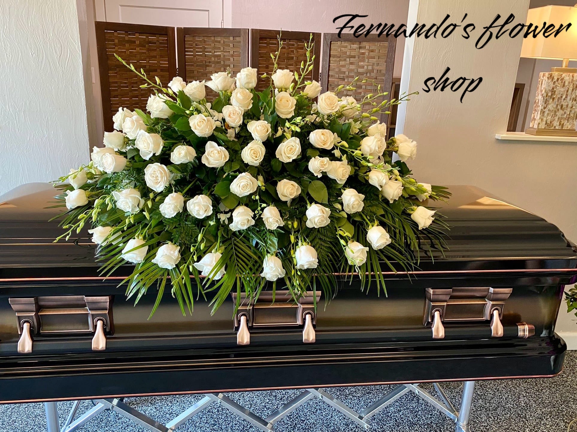 Large white rose casket spray arranged on a dark casket