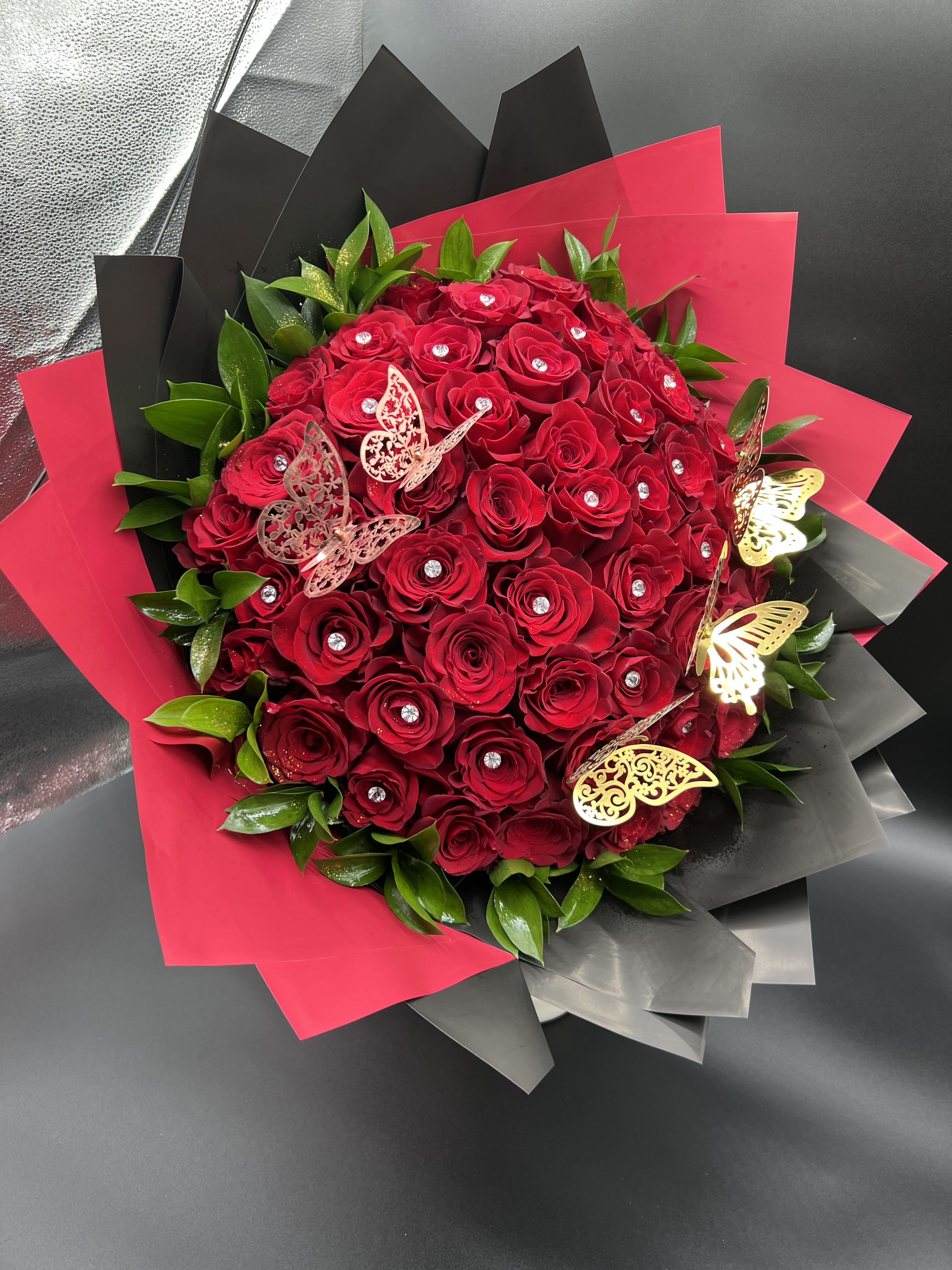 Large bouquet of red roses with crystal centers wrapped in red and black paper with gold butterflies