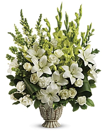 Tall white lily and rose arrangement with green accents in an ornate pedestal vase