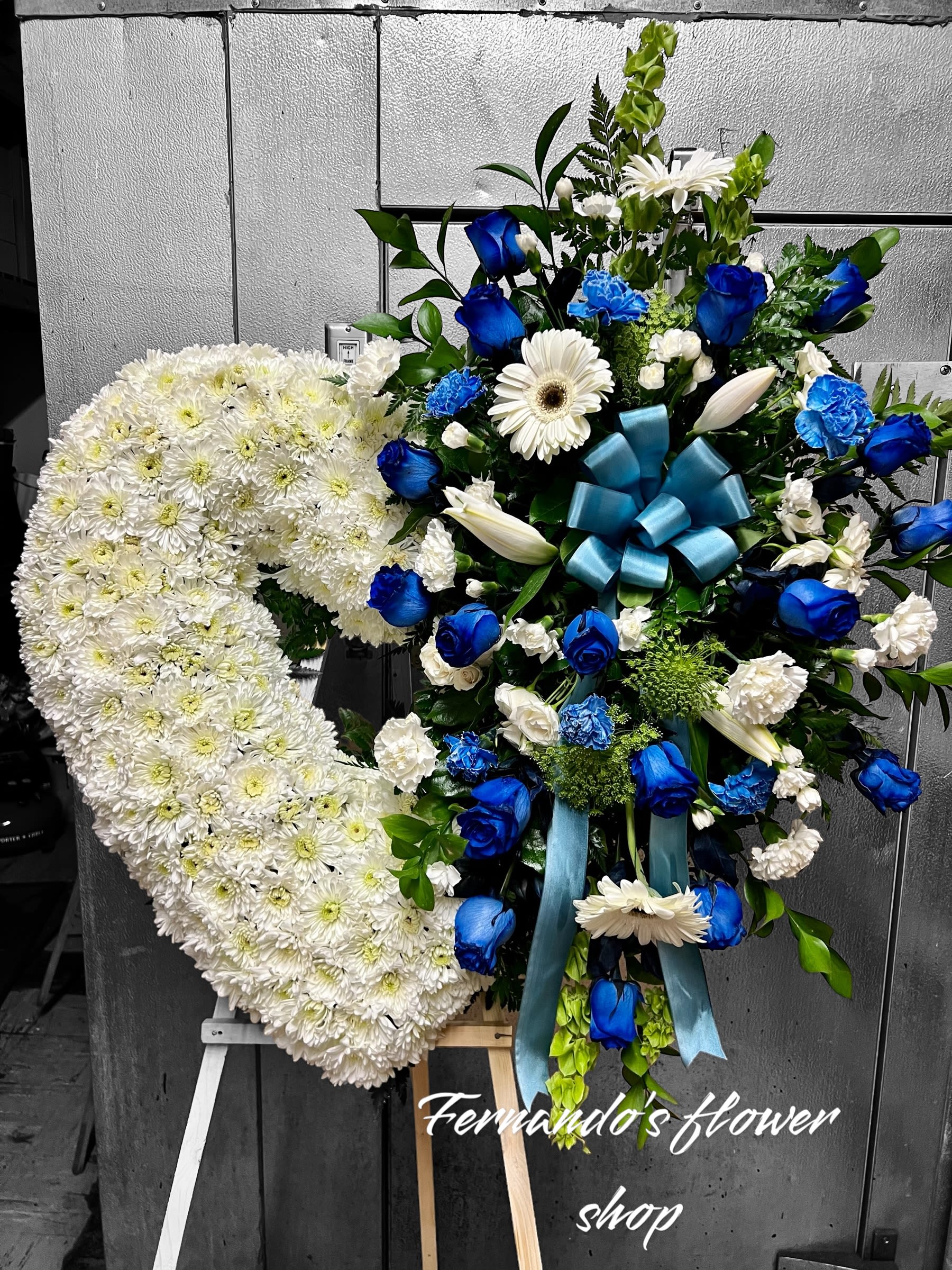 Standing sympathy easel with a white chrysanthemum heart and blue and white floral spray.