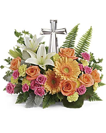 Mixed arrangement of lilies, roses, and gerbera daisies with a silver cross in the center