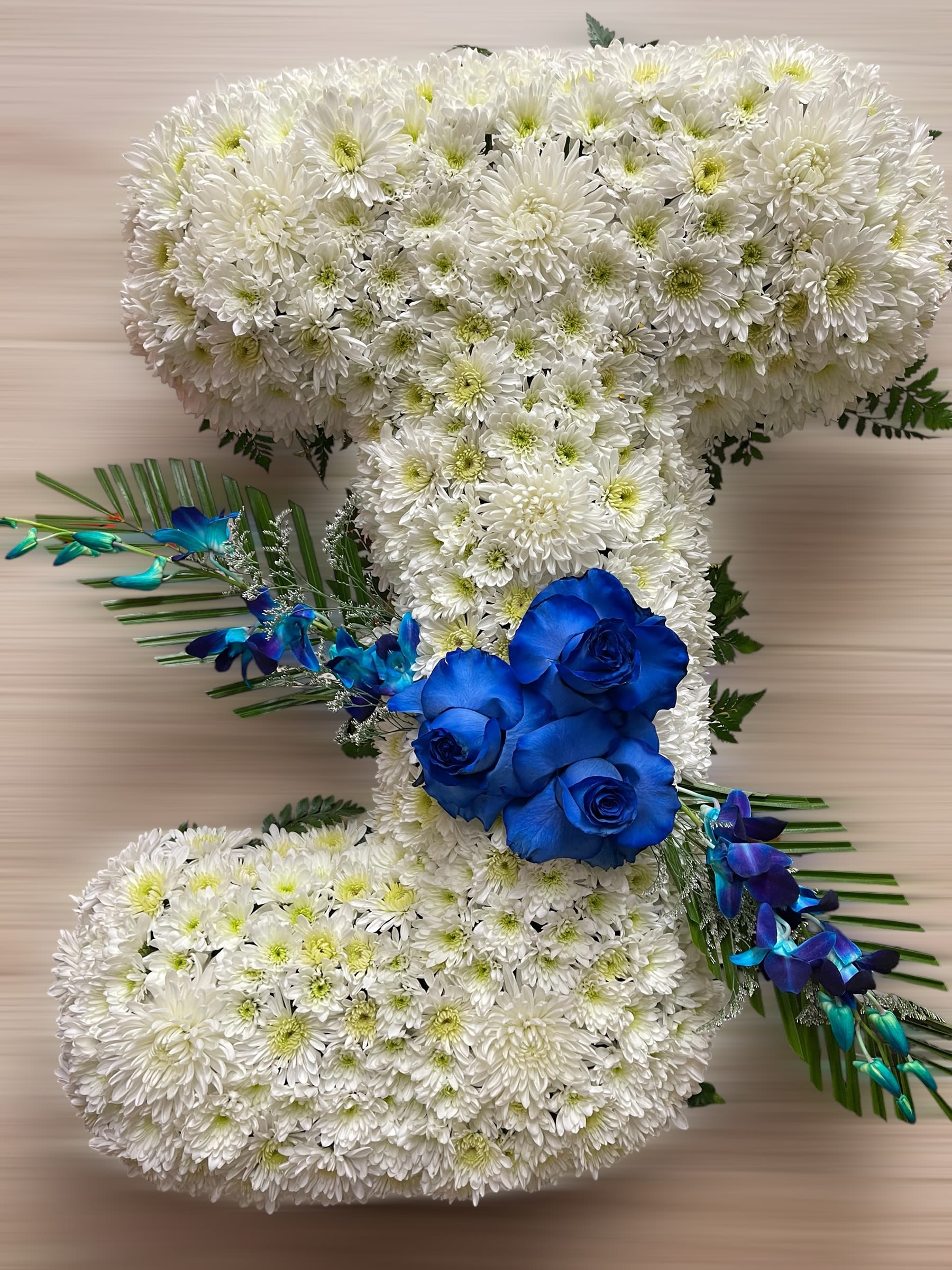 Letter J tribute of white mums with bright blue roses and orchids on a neutral background