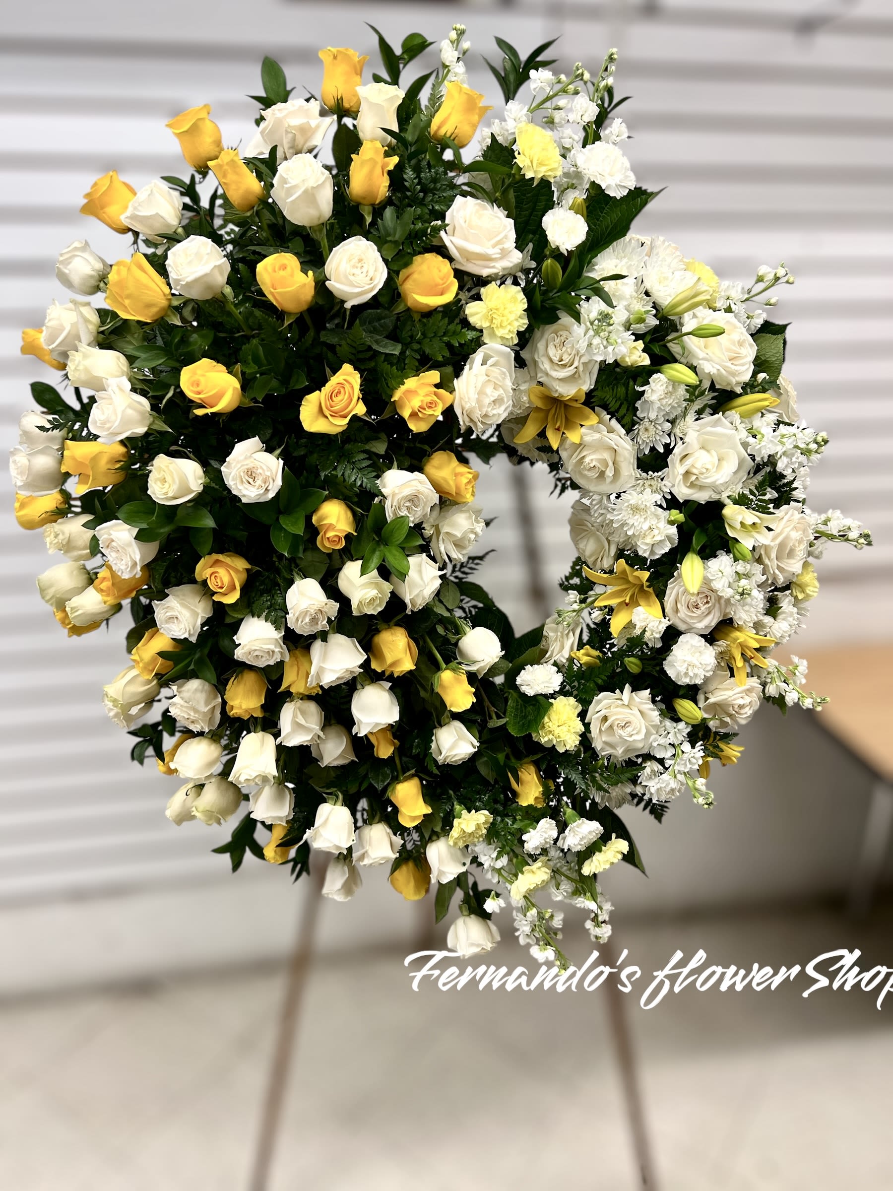 Standing open-circle wreath of white and yellow flowers on an easel