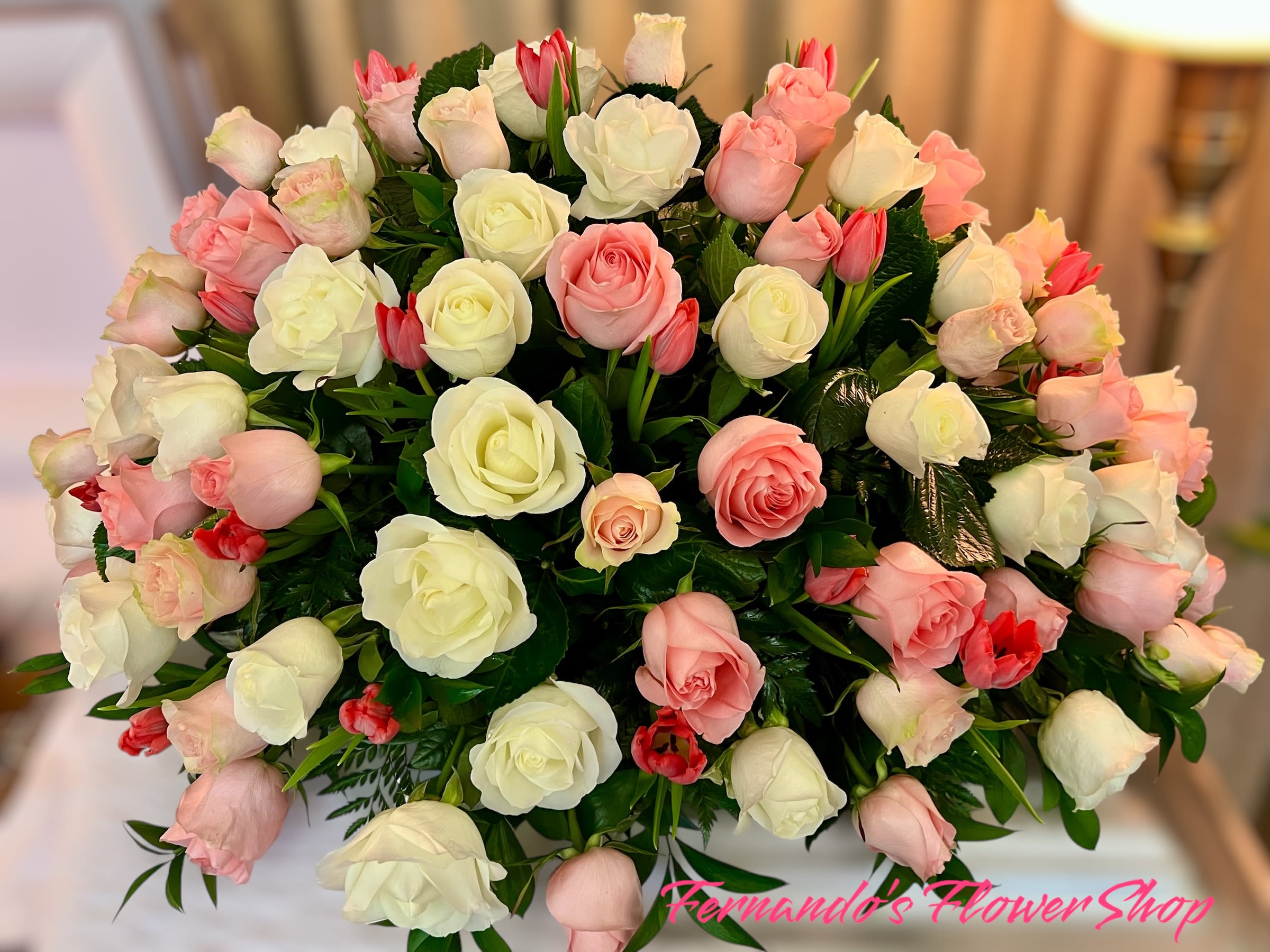 Large dome of white and blush pink roses with small red tulips in a rounded arrangement