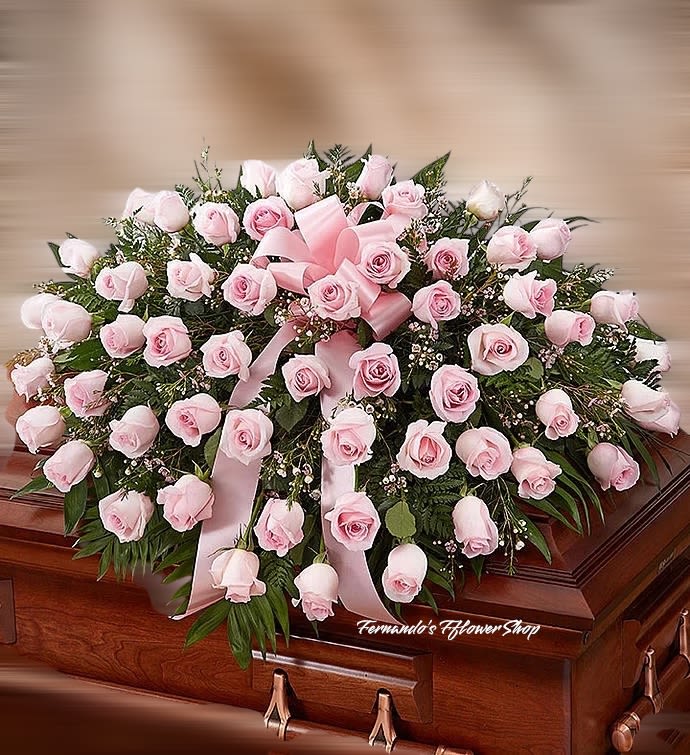 Pink rose casket spray with ribbon on a wooden casket