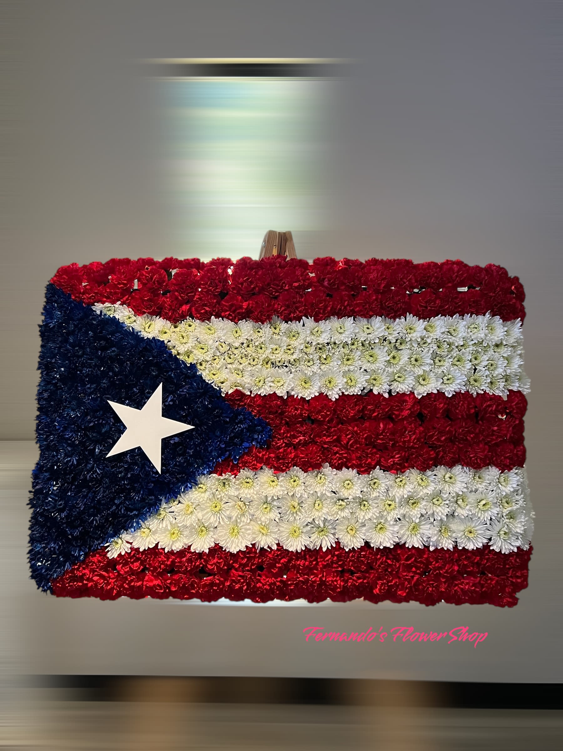 Rectangular floral arrangement styled as a red, white, and blue flag with a single white star.