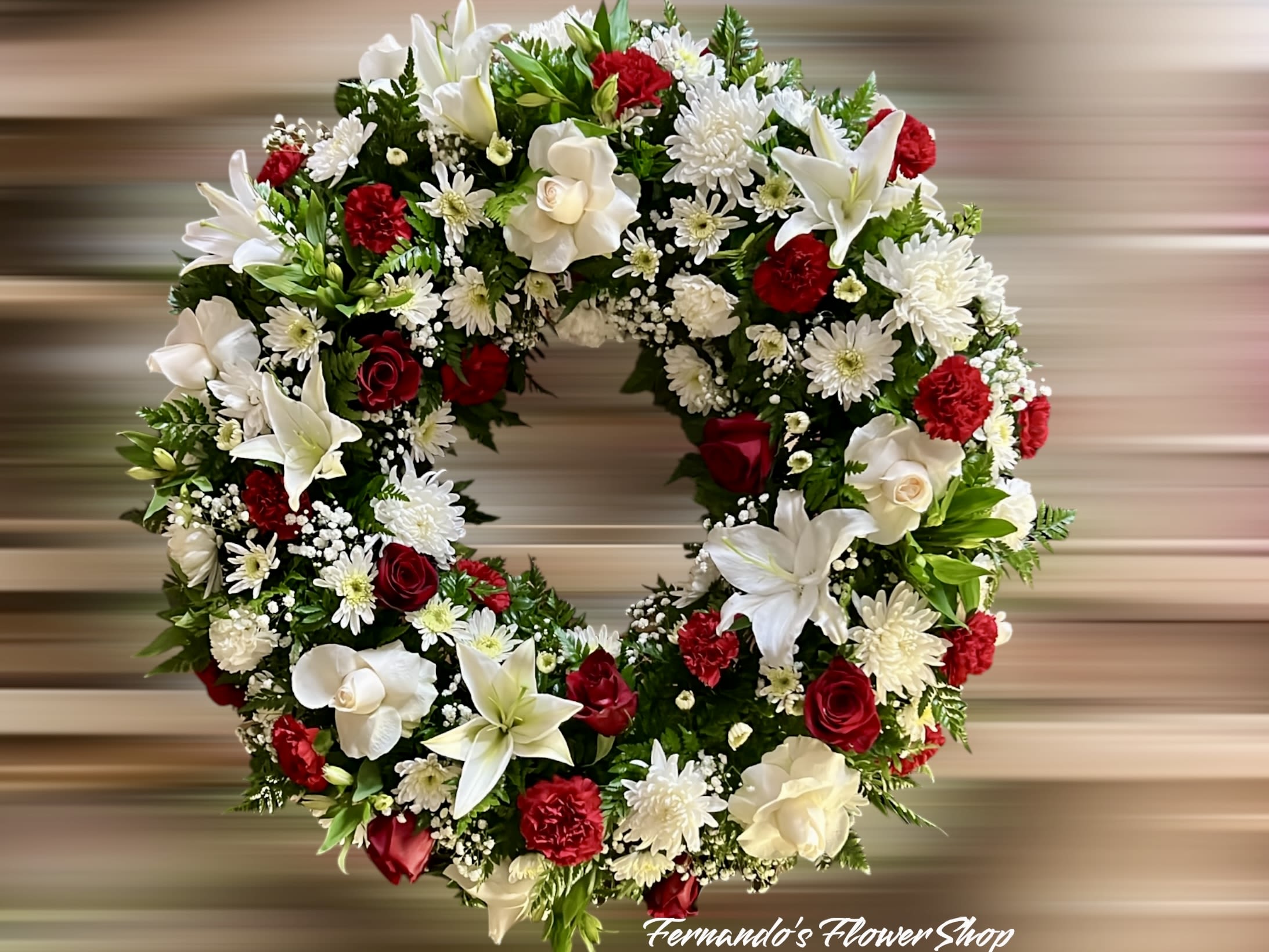 Circular wreath with white lilies, red roses, white mums, and red carnations