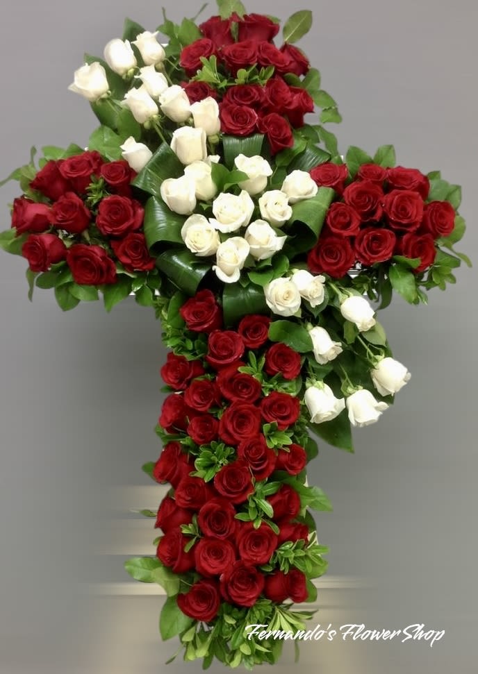 Cross-shaped arrangement of red and white roses on a neutral background