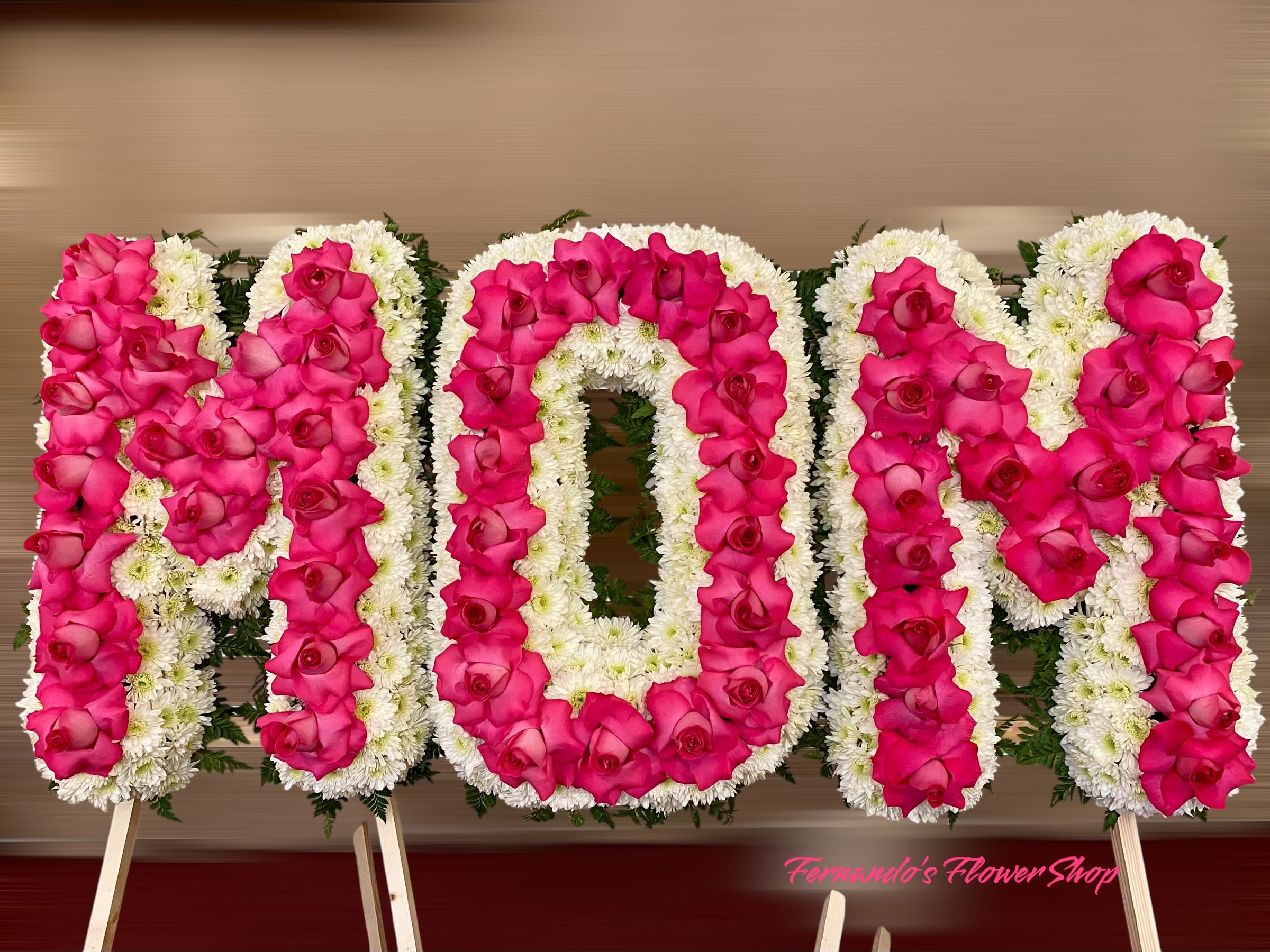 Standing floral letters spelling MOM with pink roses and white flowers on easels.
