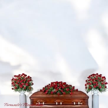Red rose casket spray with matching side arrangements on white pedestals