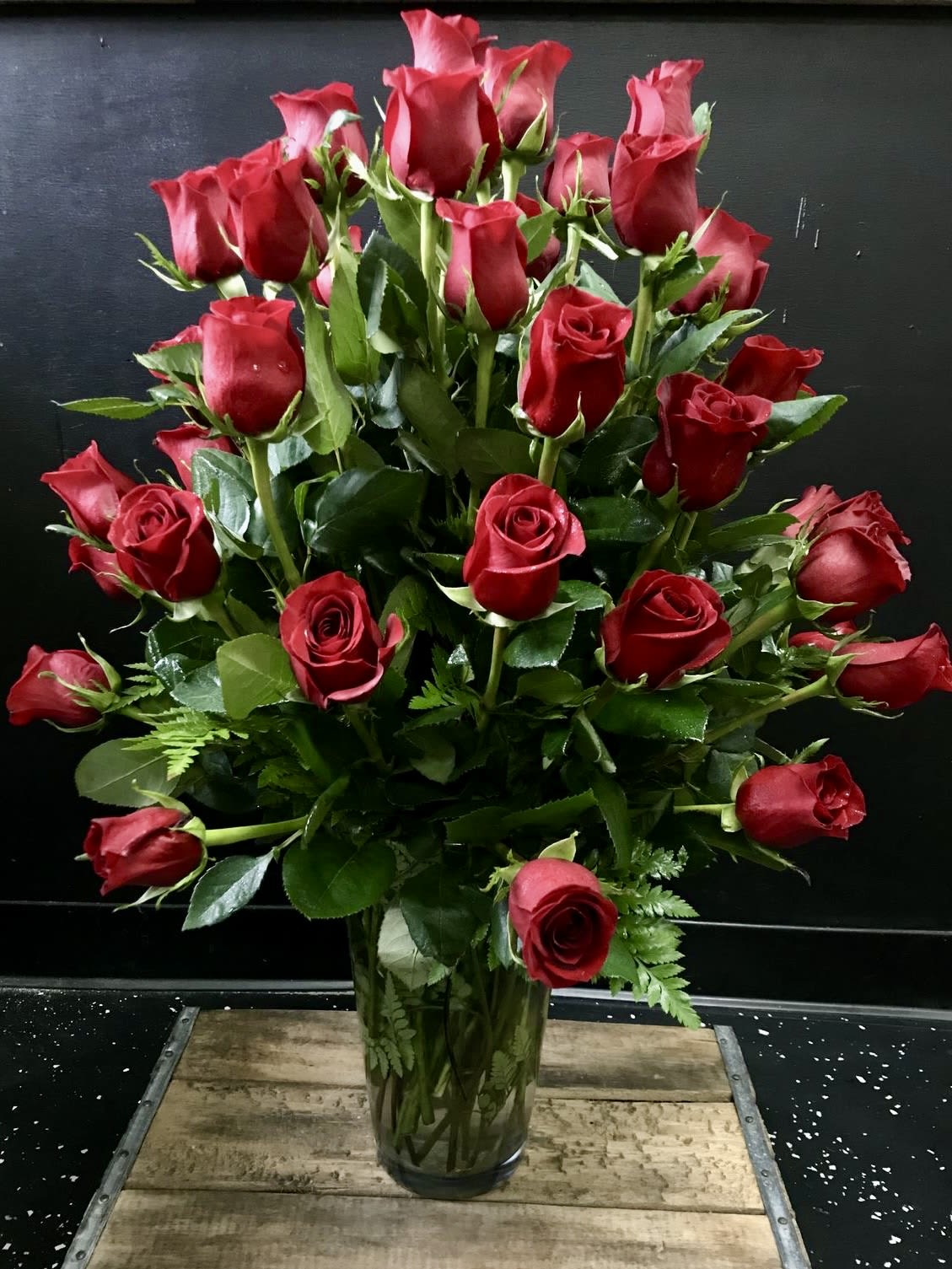 Tall arrangement of long-stemmed red roses in a clear glass vase