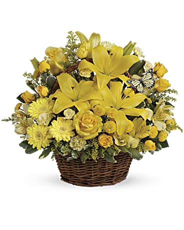 Basket arrangement of yellow lilies, roses, daisies, and mixed blooms with a small decorative butterfly accent