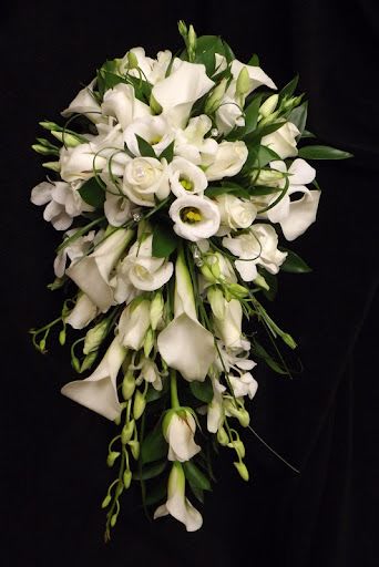 Cascading bouquet of white calla lilies, roses, and lisianthus against a black background