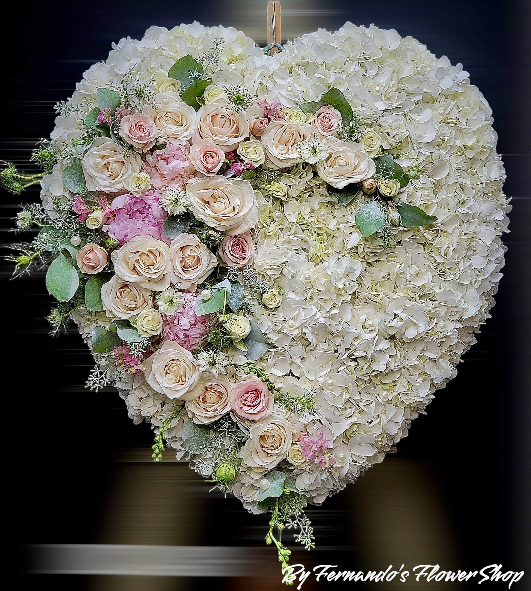 Heart-shaped white hydrangea wreath with cascading blush and pink roses.