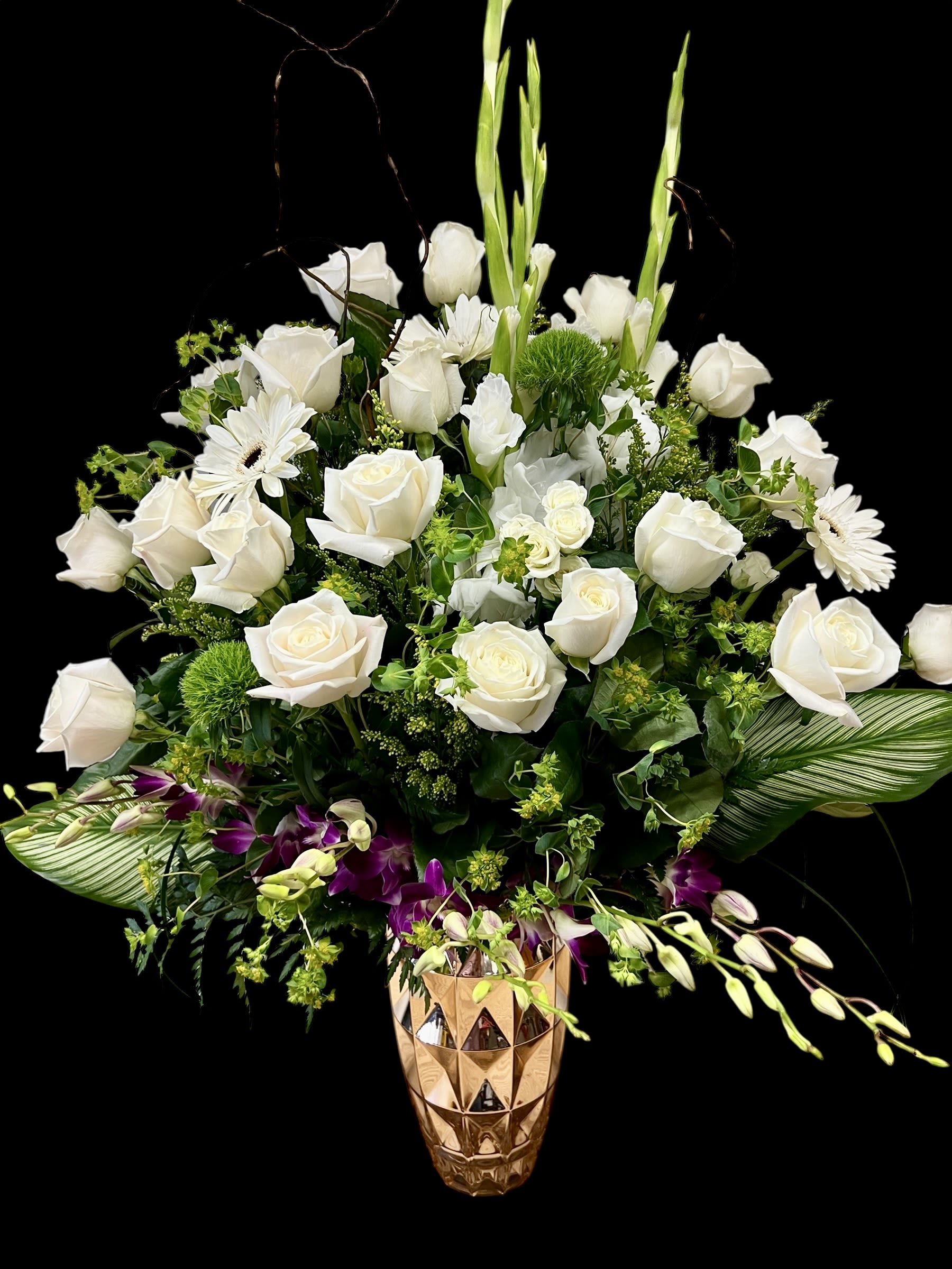 Tall white and green flower arrangement with purple orchids in a gold geometric vase