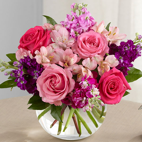 Pink and purple mixed bouquet of roses and alstroemeria in a clear glass vase