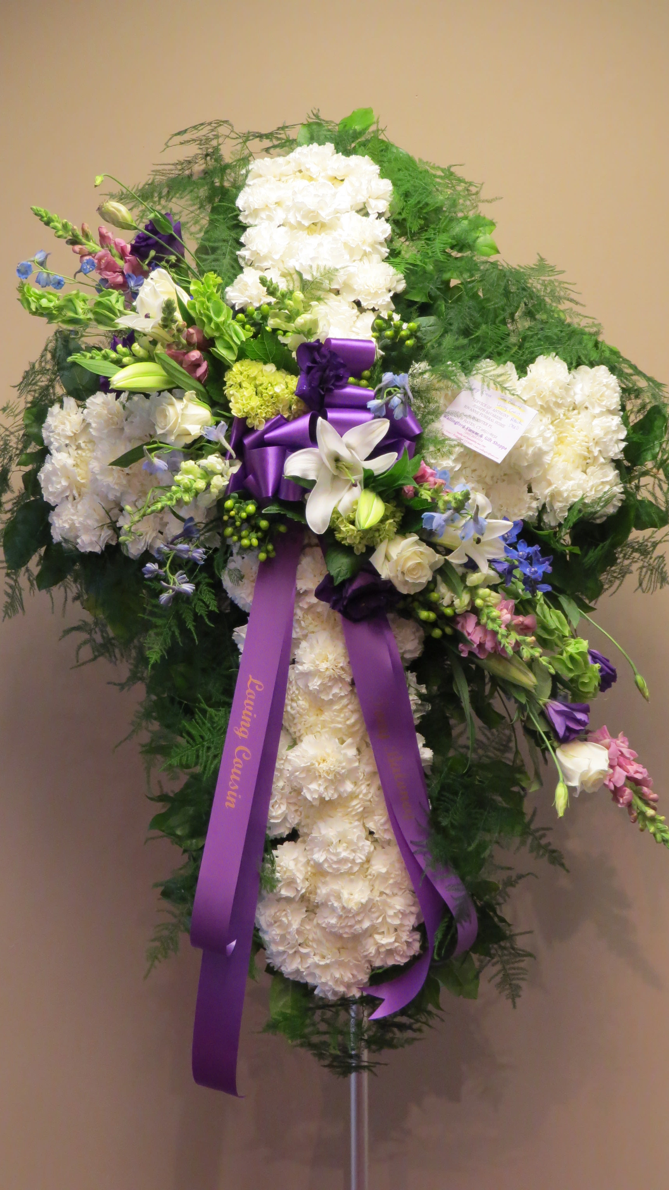 Standing white floral spray with purple ribbon and mixed blooms