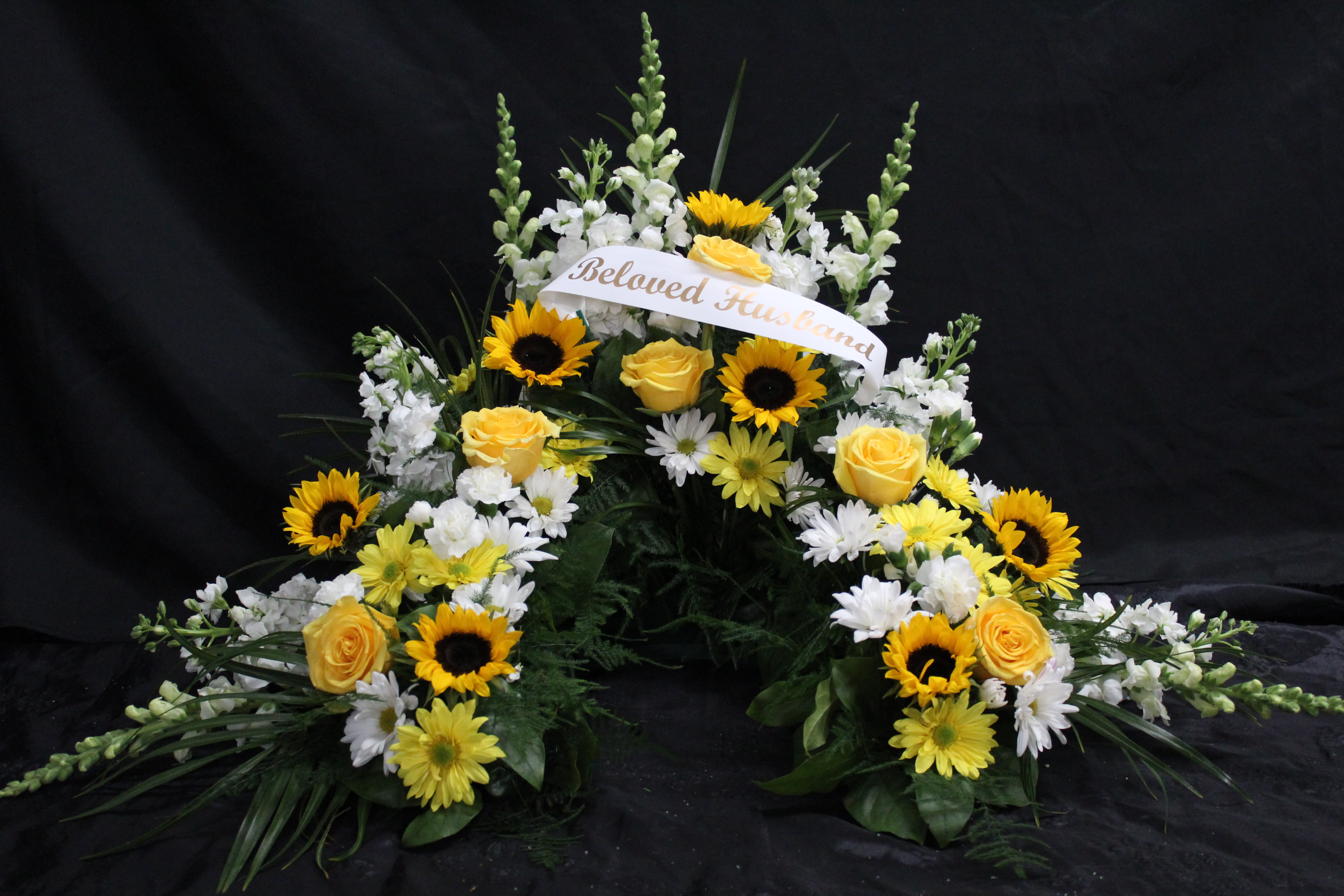 Sympathy floral spray with yellow roses, sunflowers, and white flowers