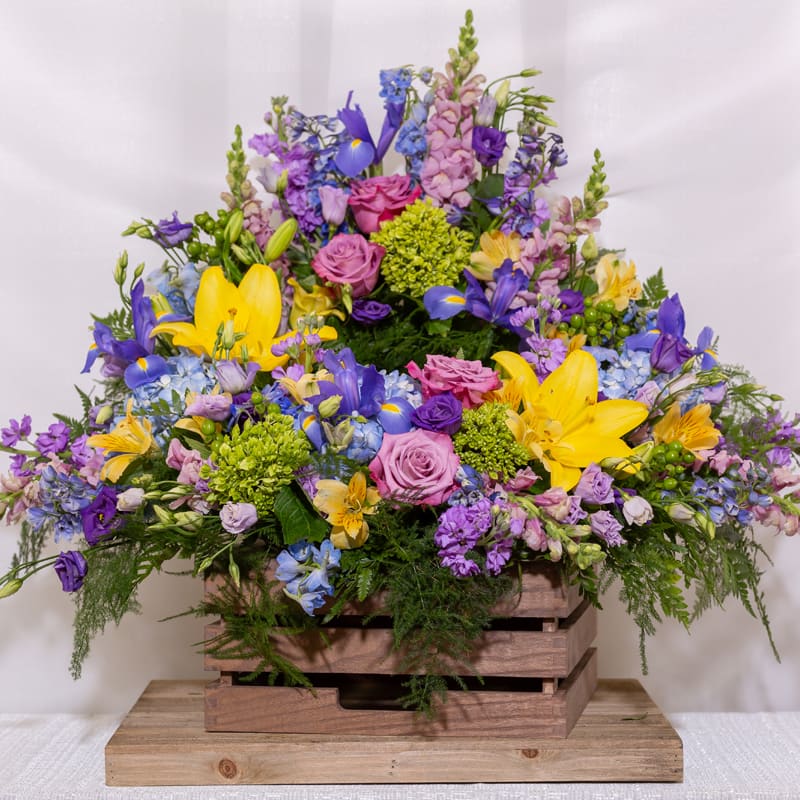Forever Remembered Urn Wreath - Blue hydrangea, green hypericum berries, purple stock dark blue delphium, soft blue delphium, lavender lisianthus, yellow lilies, green hydrandea, dark blue iris and lavender roses. 