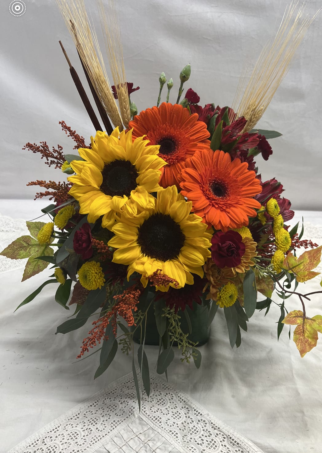Autumn Glow - This beautiful bouquet is designed in a glass cube is created using red, orange, gold, burgundy tones with Sunflowers adorned with wheat, cattails and fall leaves.  Pair this with our Pumpkin Spice Voluspa candle for the perfect finishing touch to your gift!  