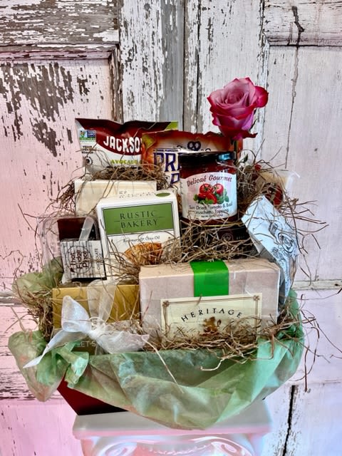 Gift basket with assorted packaged foods and a pink rose