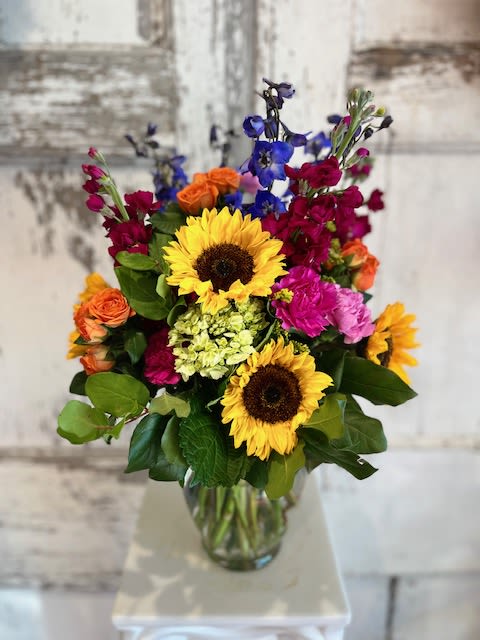 Mixed bouquet with sunflowers, roses, and colorful blooms in a glass vase
