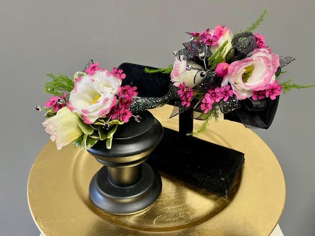 Two small floral arrangements on black stands with pink and white blooms