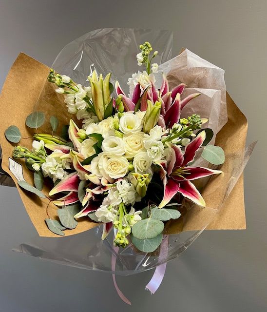 Bellissima Presentation Bouquet - Wrapped bouquet of white roses, lilies. &amp; other mixed white flowers Please note this does not come arranged in a vase, however the stems will be wrapped with a water source &amp; the recipient will place it in a vase that they have. 