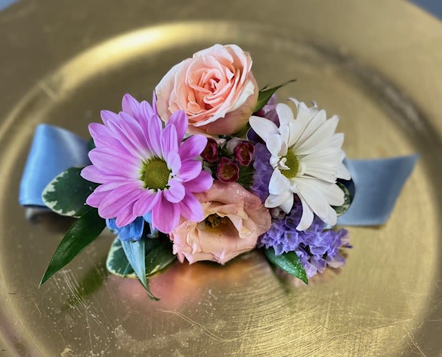 Small corsage with pink and white flowers on a blue ribbon