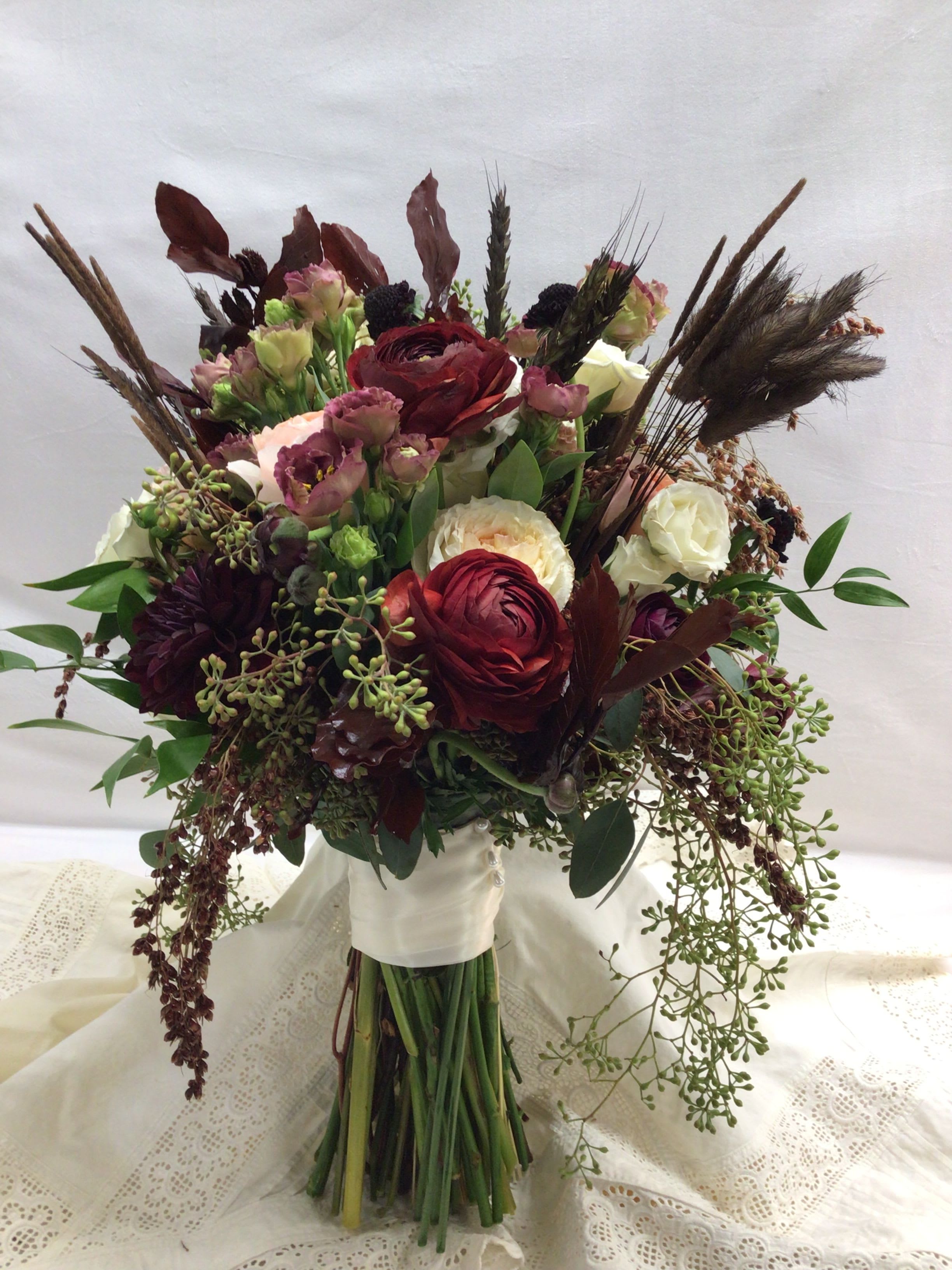 Bouquet of burgundy, cream, and pink flowers with dried accents