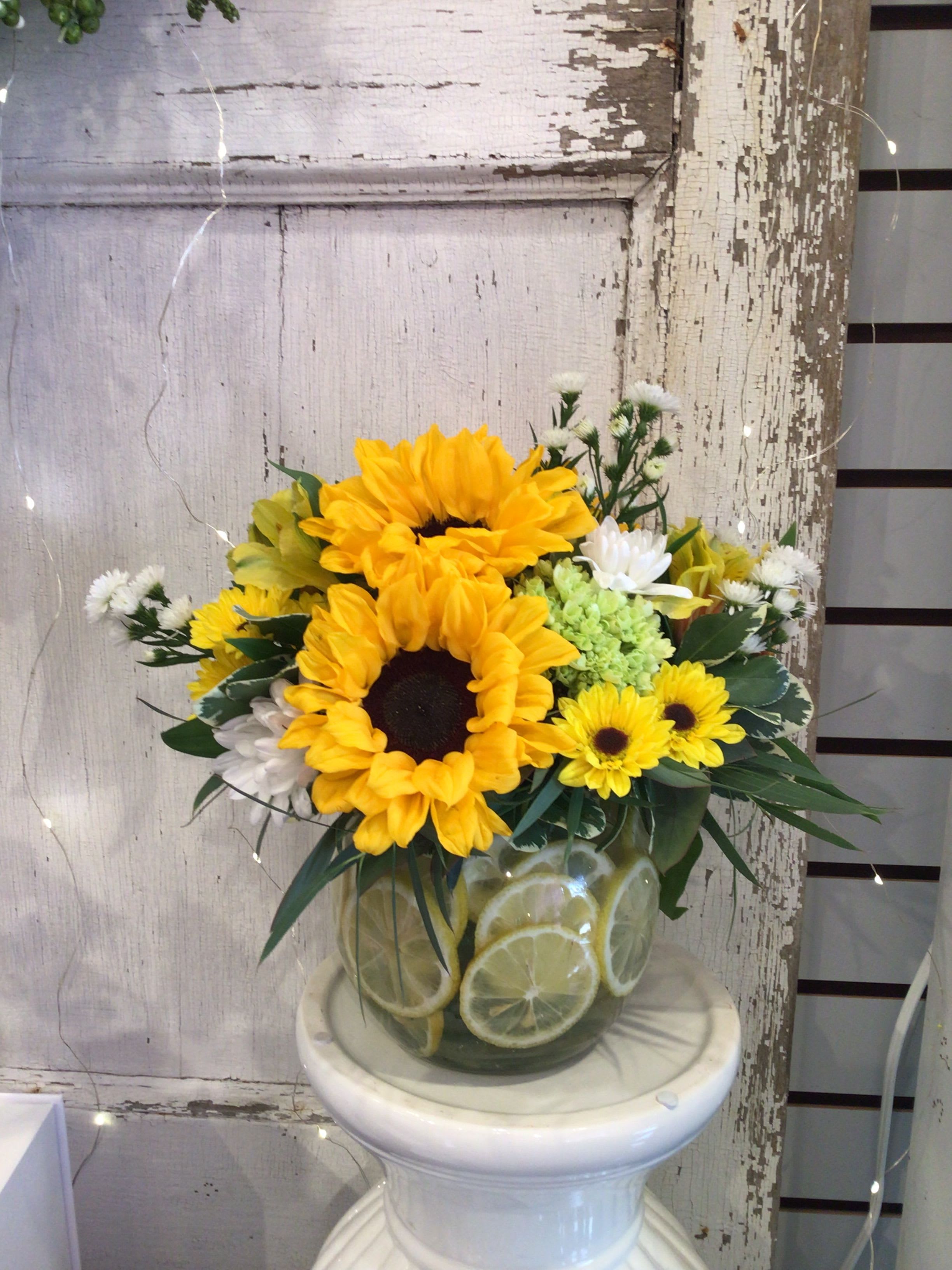 Lemonade - Seasonal garden flowers in shades of yellow complimented in a vase of lemons.