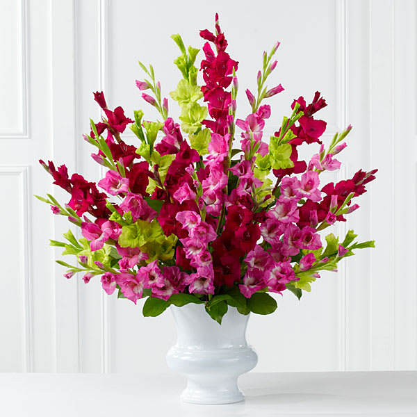 The FTD Solemn Offering Arrangement - The FTD&reg; Solemn Offering&trade; Arrangement is a bright and beautiful way to say your final farewell. Fuchsia magenta and jade gladiolus are accented with lush greens and displayed in a white plastic urn to commemorate the life of the deceased with fantastic color and elegance.