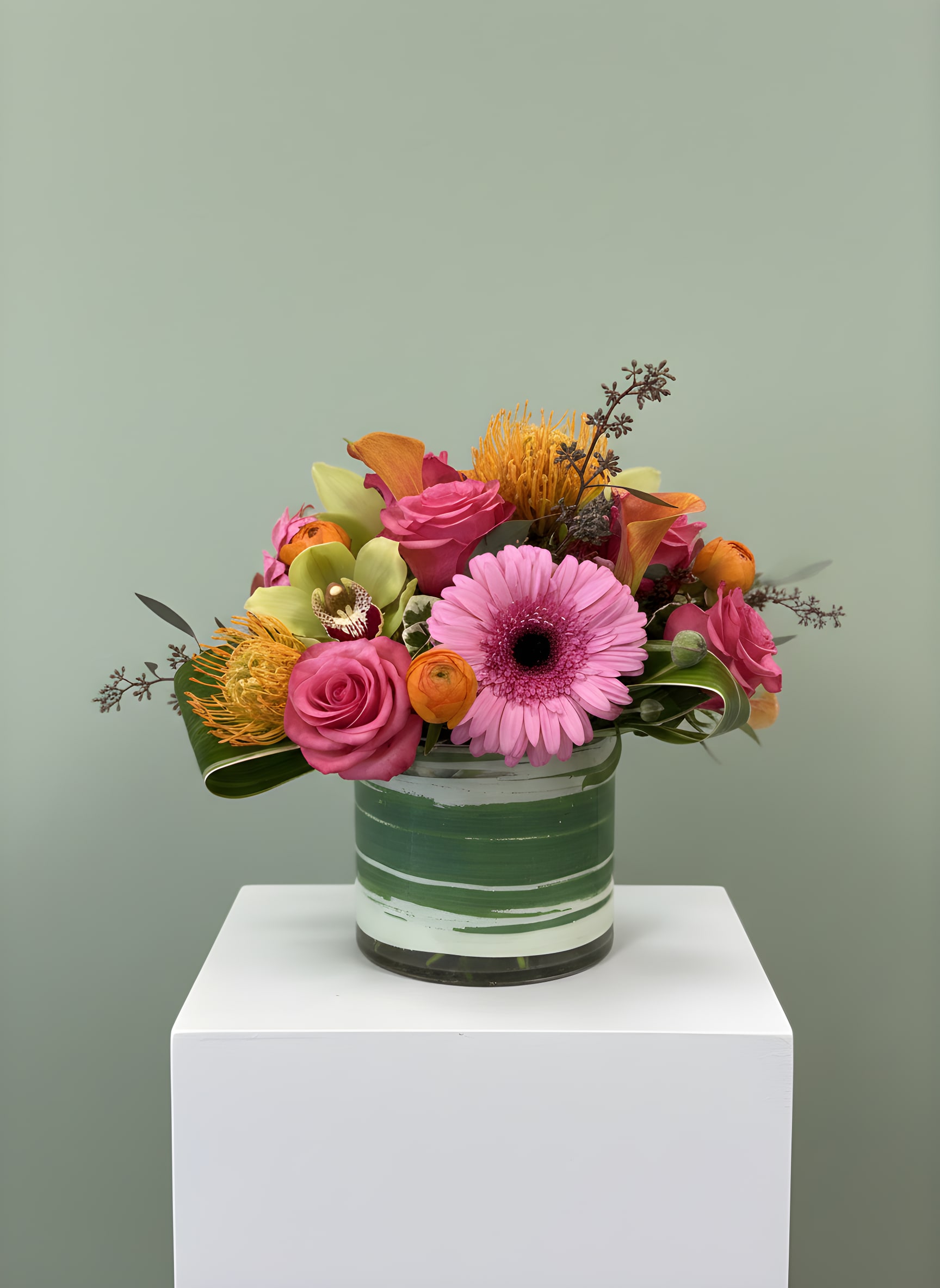 Paradiso - Paradiso is a vibrant tropical flower arrangement designed to make a lasting impression. Featuring premium pink roses, a bright pink gerbera daisy, elegant orange calla lilies, exotic green cymbidium orchids, striking pincushion protea, cheerful orange ranunculus, and seasonal premium greenery, this stunning design is arranged in a modern green glass cylinder vase. Bursting with rich color and unique textures, Paradiso is the perfect choice for birthdays, anniversaries, congratulations, thank you gifts, get well wishes, housewarmings, or simply brightening someone's day. Its bold tropical style brings warmth and elegance to any home or office while showcasing some of the freshest flowers available. Handcrafted by the designers at All Occasions Florist, every arrangement is made with care using the highest-quality blooms. Proudly offering same-day flower delivery in Dallas, Richardson, Highland Park, University Park, Plano, Garland, Mesquite, and surrounding communities, Paradiso is a beautiful way to send fresh flowers for any occasion. Flower varieties may vary slightly based on seasonal availability while maintaining the overall style, color palette, and value of the arrangement.