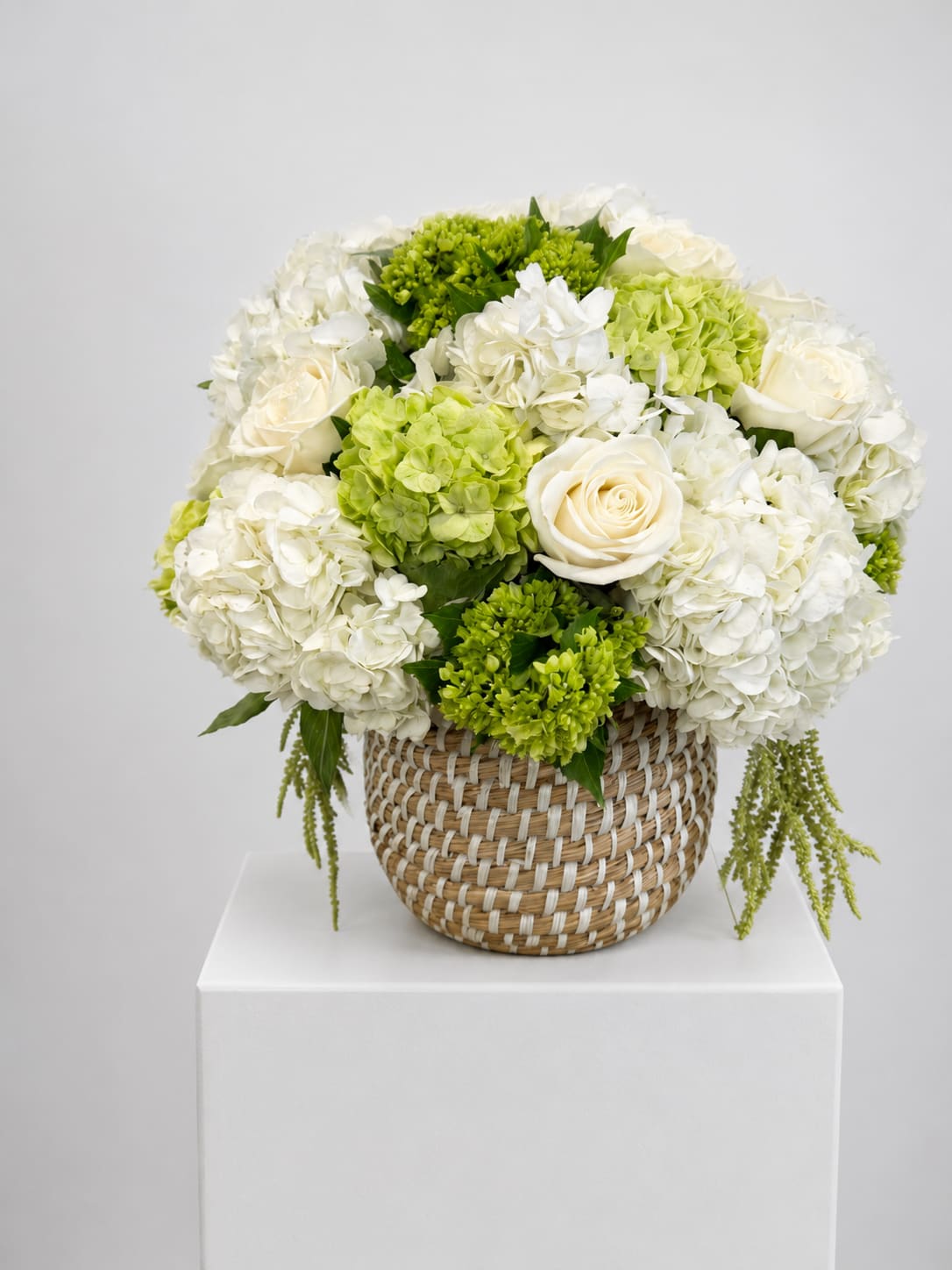 White and green floral arrangement in a woven basket