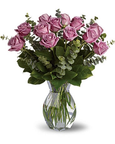 Arrangement of lavender roses with eucalyptus in a clear glass vase