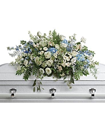 White and blue mixed flower casket spray on a white casket