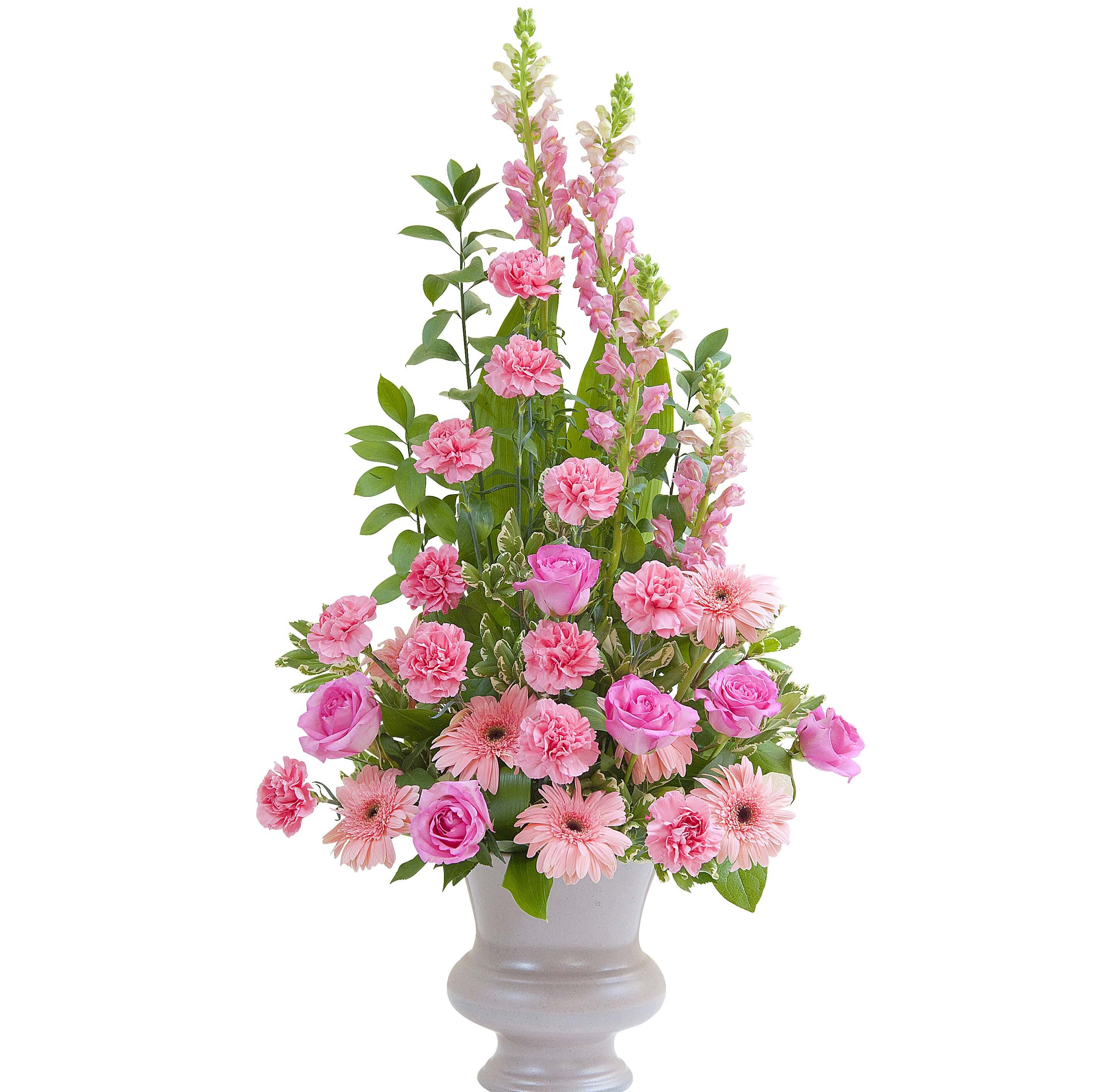 Tall pink arrangement with roses, carnations, gerbera daisies, and snapdragons in a pale pedestal vase