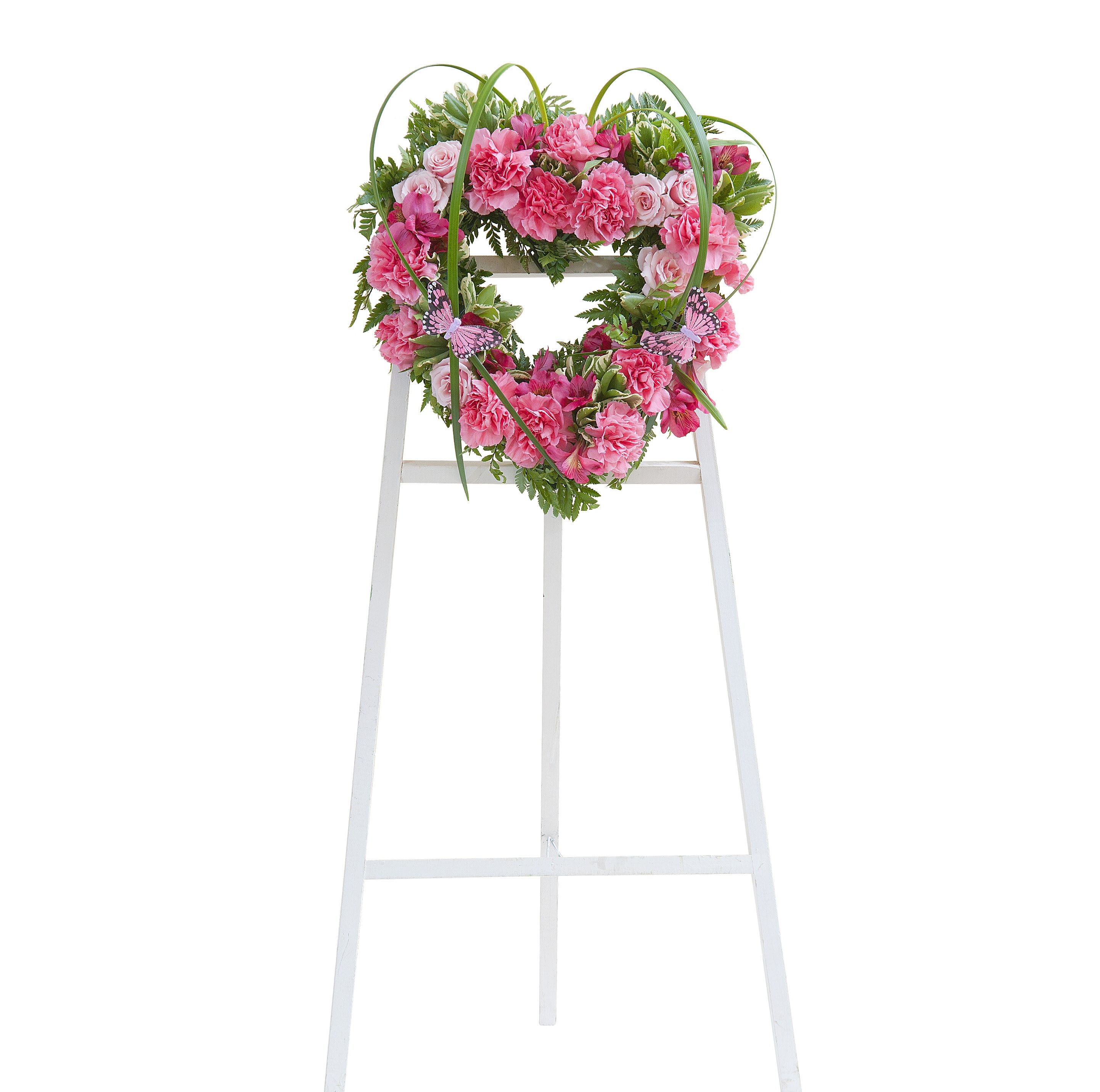 Heart-shaped wreath of pink flowers on a white easel stand
