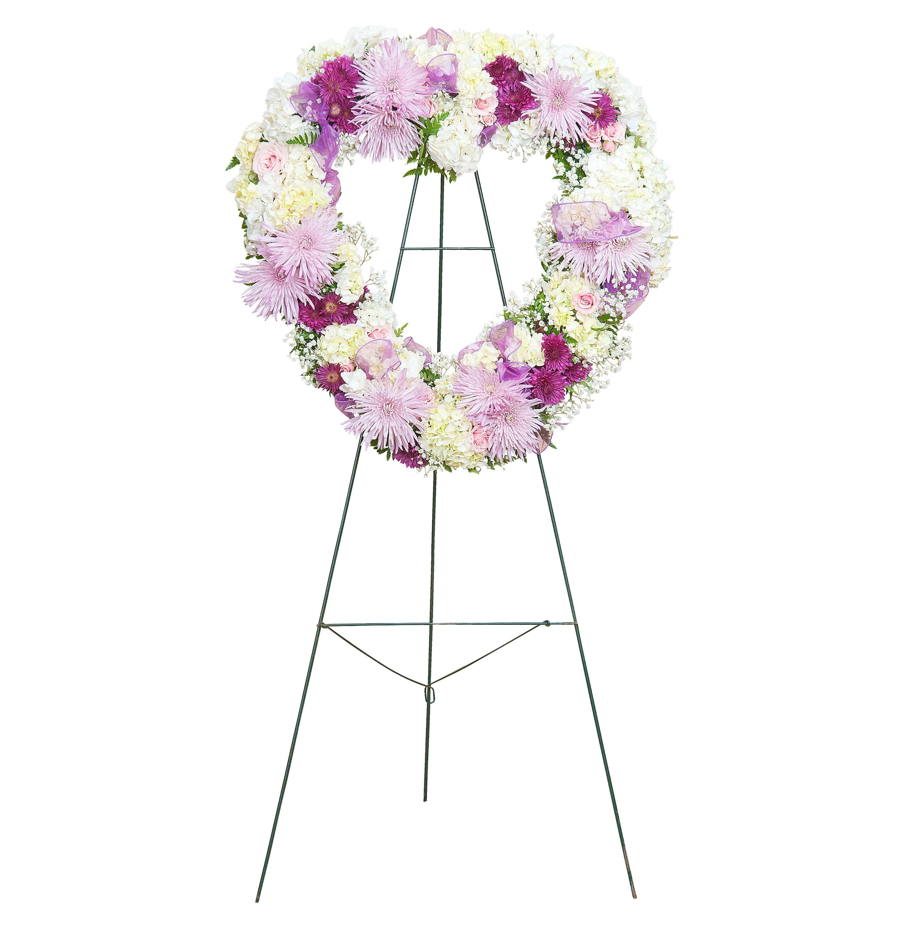 Heart-shaped standing wreath with white, lavender, and purple flowers on a metal easel