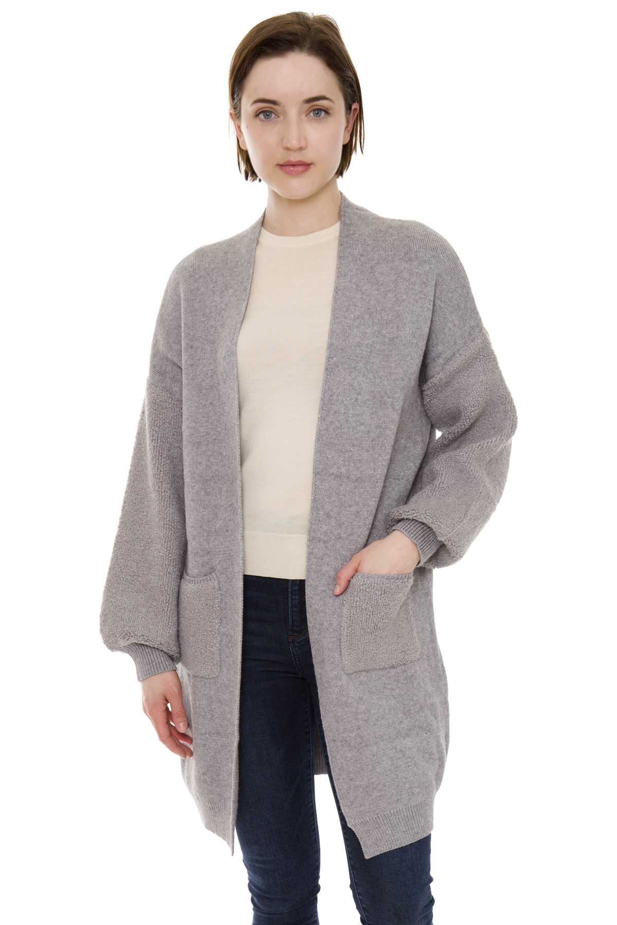 Woman wearing a long gray open-front cardigan over a light top and dark jeans