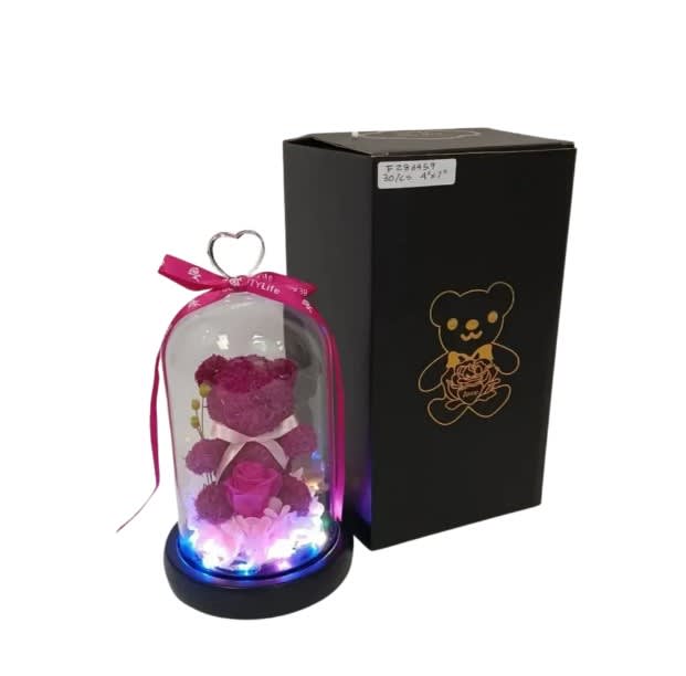 Pink teddy bear and artificial rose under glass dome with lights beside black gift box