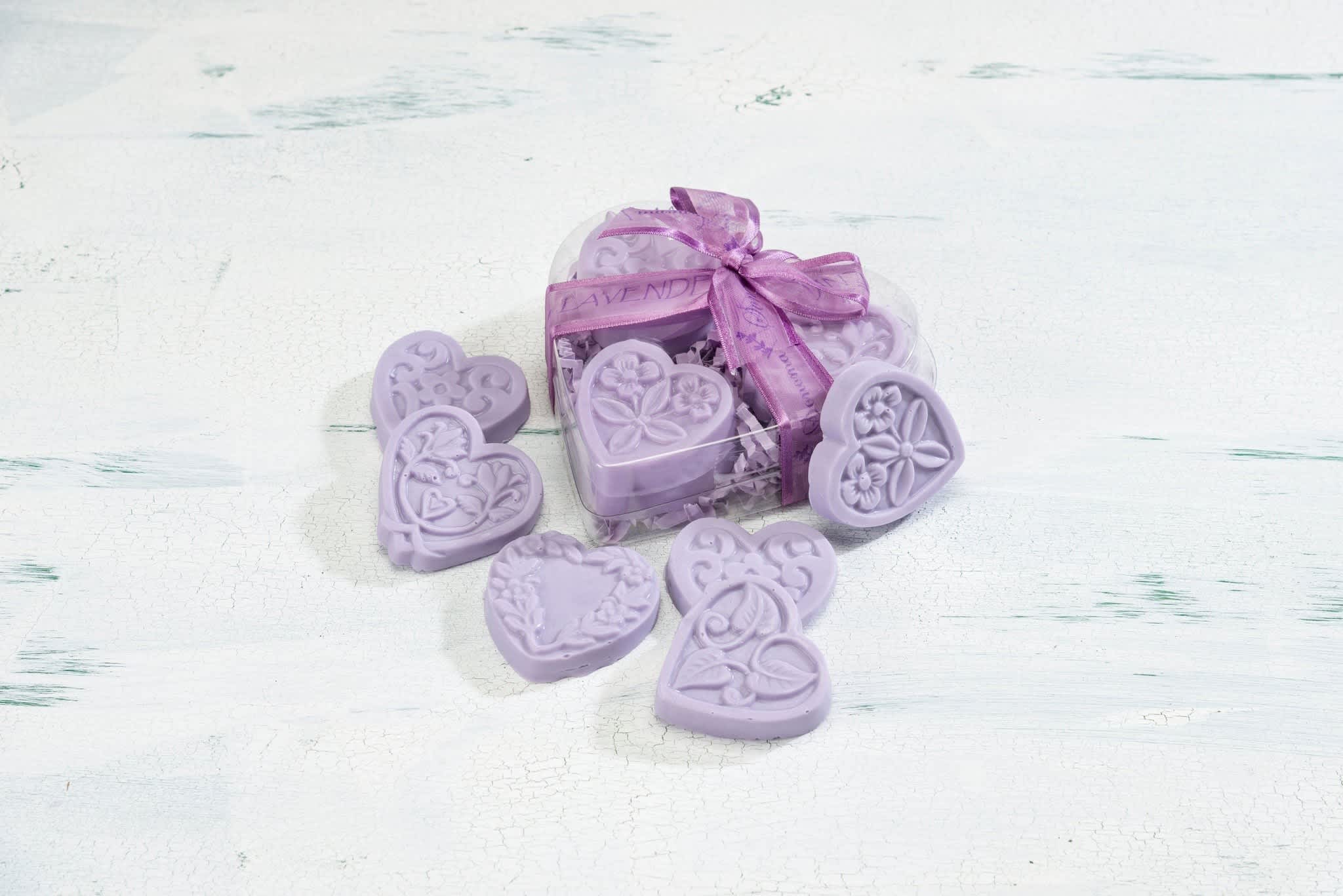 Heart-shaped lavender soaps in a clear heart box with a purple ribbon and soaps scattered around it.