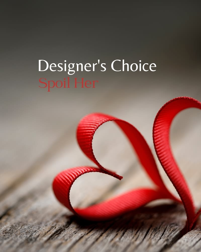 Red ribbon curled into a heart shape on weathered wood with text reading Designer's Choice Spoil Her