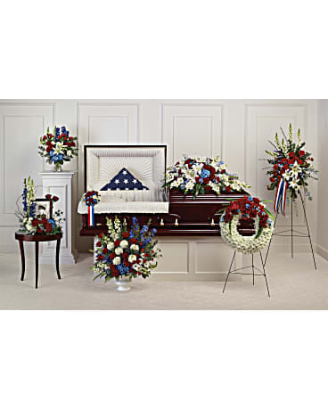 Patriotic red, white, and blue funeral floral set around an open casket with a folded flag