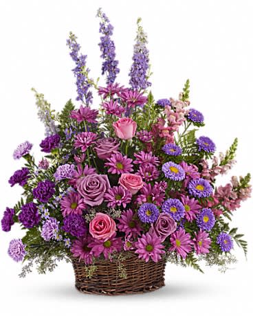 Tall basket arrangement of pink roses, purple daisies, asters, and delphinium in mixed lavender tones