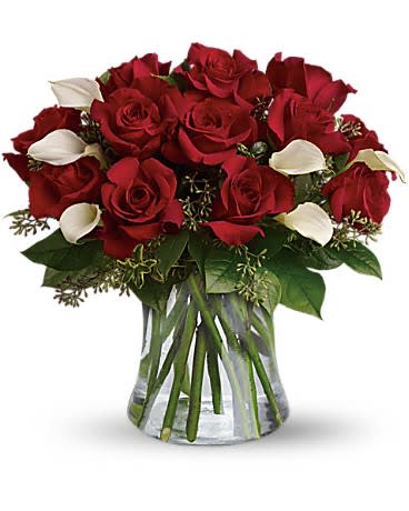 Arrangement of red roses and white mini calla lilies in a clear glass vase