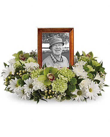 Low wreath of white daisies and green flowers encircling a wooden-framed portrait