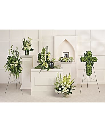 Sympathy floral collection in white and green with standing sprays and a cross-shaped arrangement.