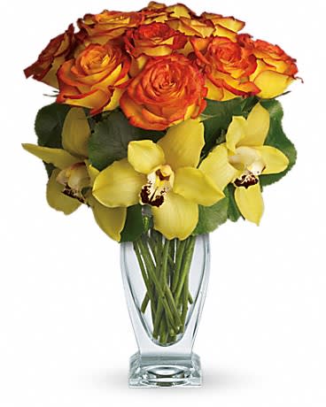 Tall clear vase with orange-yellow roses and yellow orchids in a compact arrangement